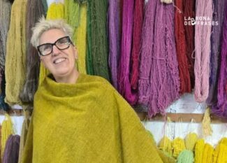 Ermi Fernández, artista de Tramas Convergentes, con un chal de lana frente a madejas teñidas con tintes naturales