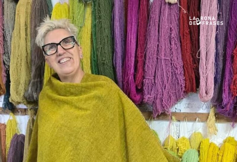 Ermi Fernández, artista de Tramas Convergentes, con un chal de lana frente a madejas teñidas con tintes naturales